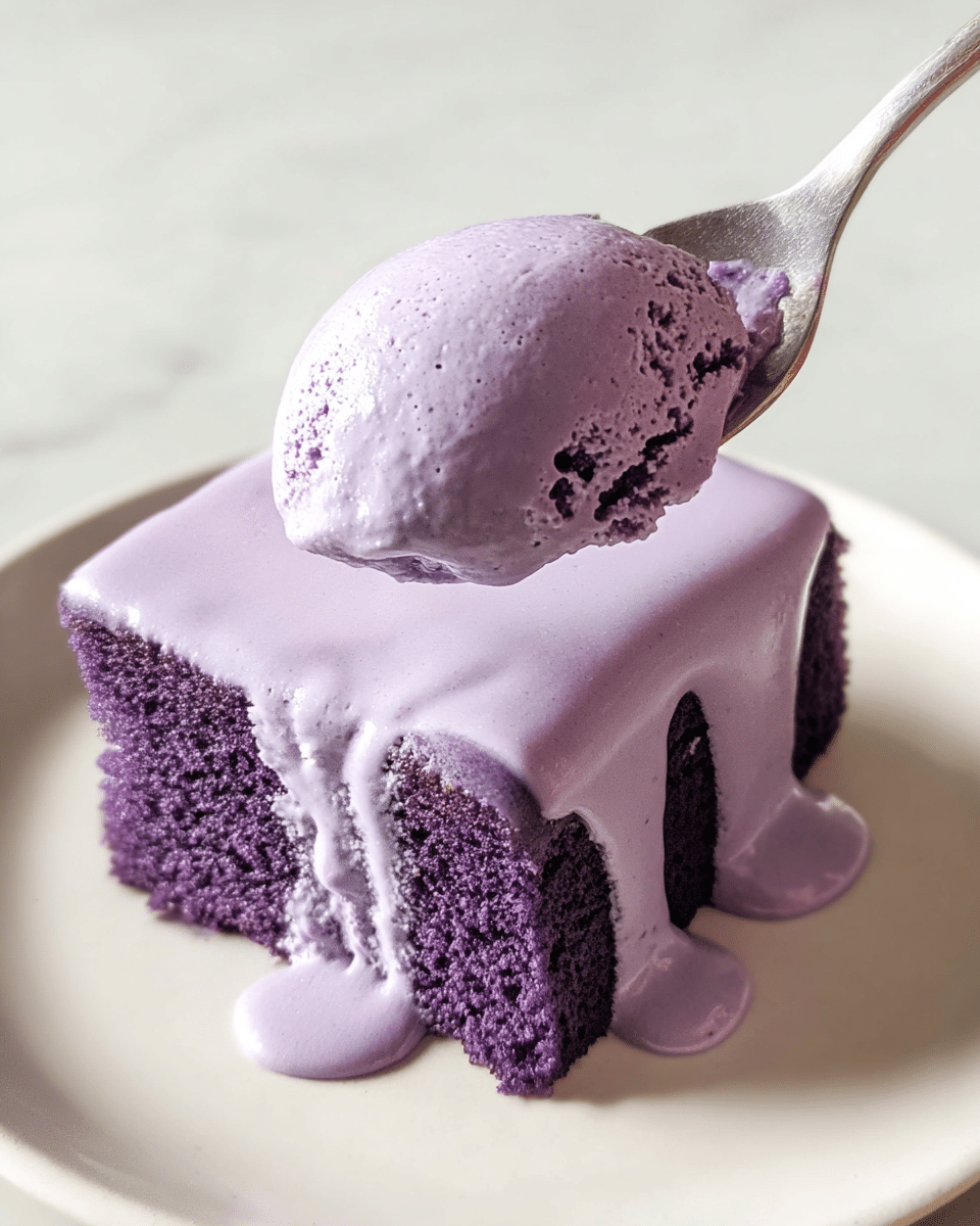 A small square piece of purple sponge cake sits on a white plate, covered by a thick, shiny layer of light purple cream that drips down the sides. A spoon holds a scoop of the purple cake with cream on top, showing the soft and airy texture of the cake with small holes. The light purple cream looks smooth and fluffy, while the darker purple cake underneath is moist and dense with a slightly rough surface. The scene is bright with a clean white marbled texture under the plate. photo taken with an iphone --ar 4:5 --v 7