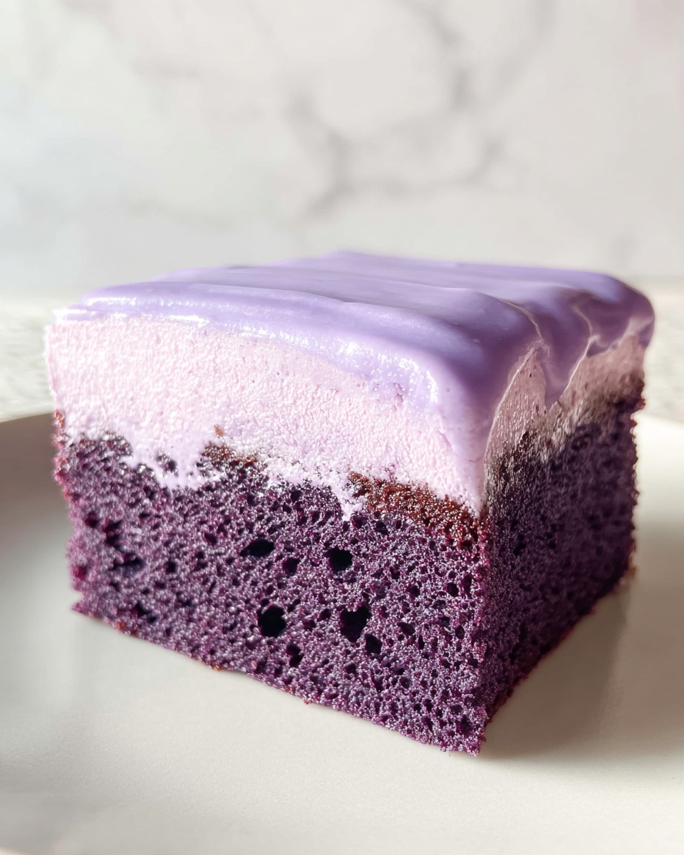 A single square slice of purple cake is shown sitting on a white plate with a soft texture. The cake has two layers: the bottom layer is a dark purple sponge cake with small air holes, appearing moist and dense. The top layer is a lighter purple, creamy frosting with a smooth and slightly glossy surface, covering the entire top and slightly dripping down the sides. The background features a white marbled texture. photo taken with an iphone --ar 4:5 --v 7