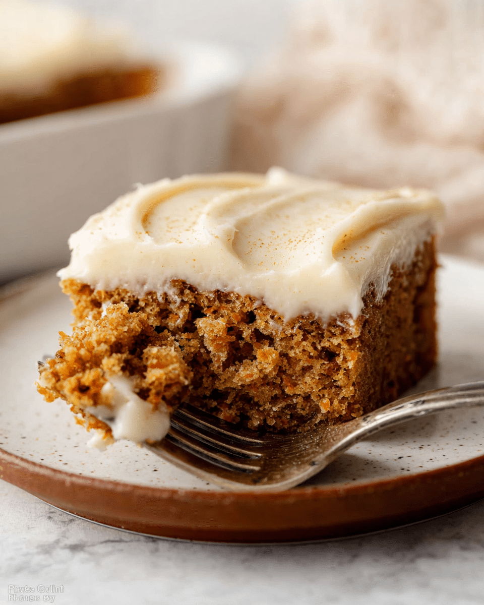 A close-up of a single square piece of carrot cake on a white plate with a brown rim, showing two layers: the bottom layer is a moist, crumbly, medium-brown cake with visible texture, and the top layer is a thick, creamy, off-white frosting, smooth with a few small specks on top. A fork is cutting into the frosting and cake, lifting a bite-sized piece. The background features a soft white marbled texture. Photo taken with an iphone --ar 4:5 --v 7