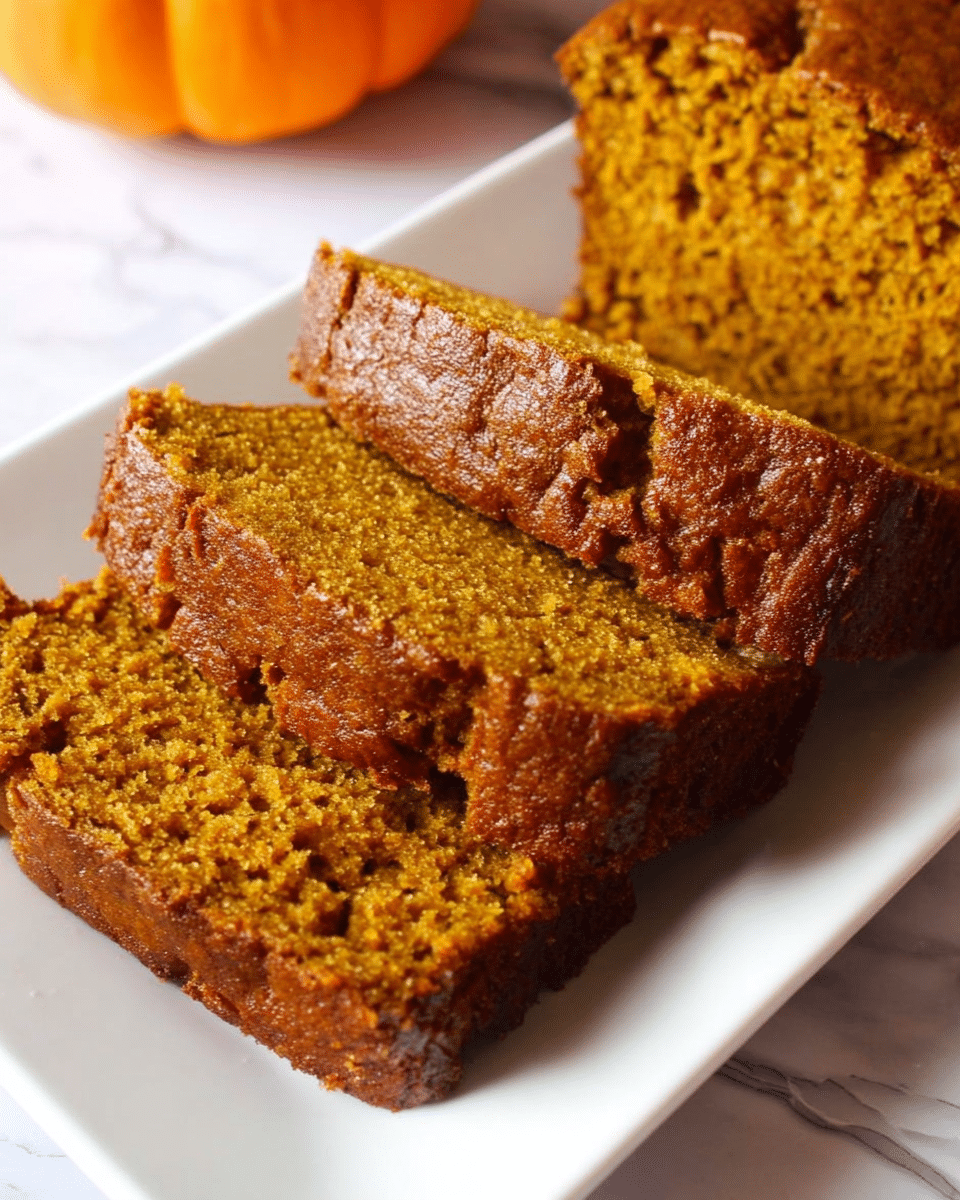 The image shows three slices of moist pumpkin bread placed on a white rectangular plate. The bread has a rough, crumbly texture with a warm brown color and darker crust edges. The slices are stacked slightly overlapping each other, showing the dense inside of the bread. The background has a white marbled texture with a small part of a pumpkin visible in the top left corner. photo taken with an iphone --ar 4:5 --v 7