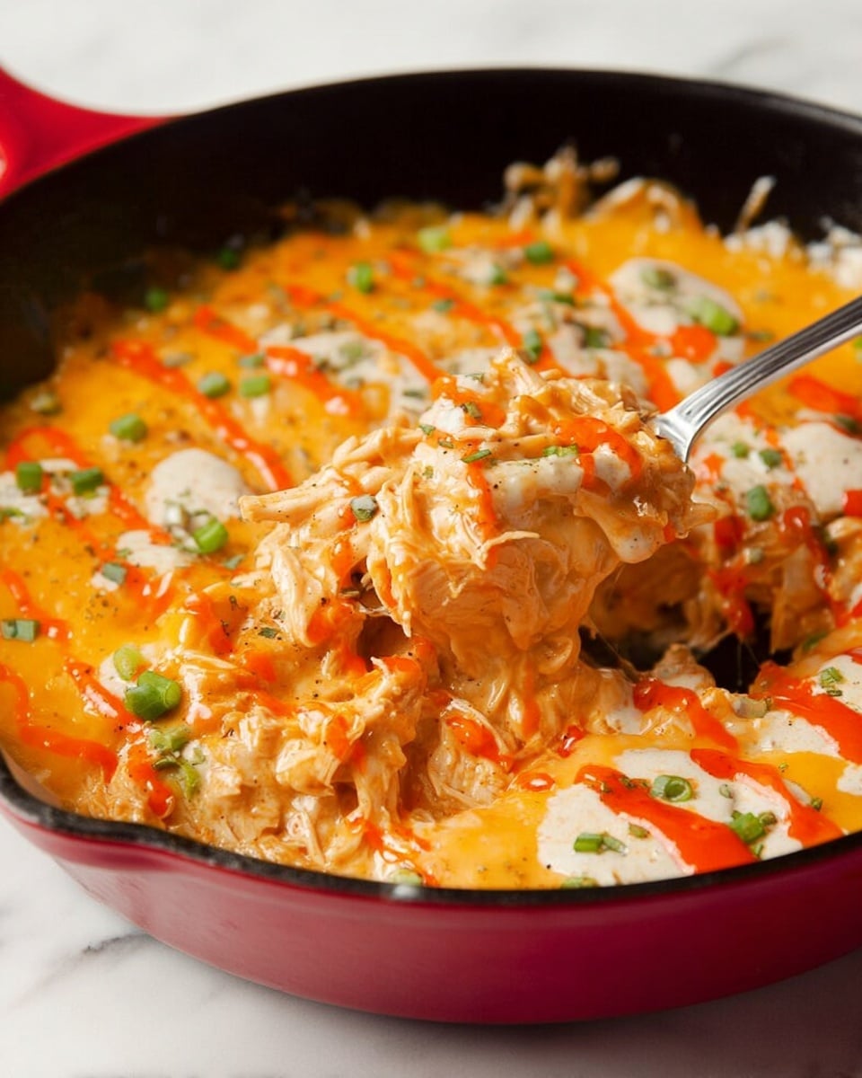 The image shows a cooked dish in a red cast iron skillet with a black inside. The dish has three visible layers: a base layer of soft, shredded orange chicken mixed with a creamy sauce, a middle layer of melted yellow-orange cheddar cheese spread evenly on top, and several dollops of white creamy sauce mixed with green herbs scattered across the cheese. There are splashes of bright red sauce drizzled in lines over the cheese, and chopped green onions sprinkled on top adding some green color. A silver fork is scooping into the dish, lifting a portion of the cheesy, creamy chicken mixture. The skillet sits on a white marbled surface. Photo taken with an iphone --ar 4:5 --v 7