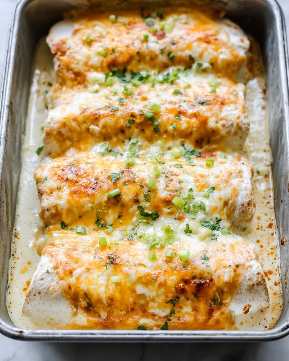 Three layered rolled burritos sit close together in a silver rectangular baking pan, each covered with melted cheese that is golden and bubbly on top. The burritos have a soft, light beige tortilla base underneath the cheese. The cheese layer has different shades of yellow and white melted together, with small bits of chopped green onions and herbs sprinkled evenly on top. The pan is filled with creamy sauce that bubbles around the edges, showing a light yellow and white color with some brown spots from baking. The whole image is set against a white marbled background. photo taken with an iphone --ar 4:5 --v 7
