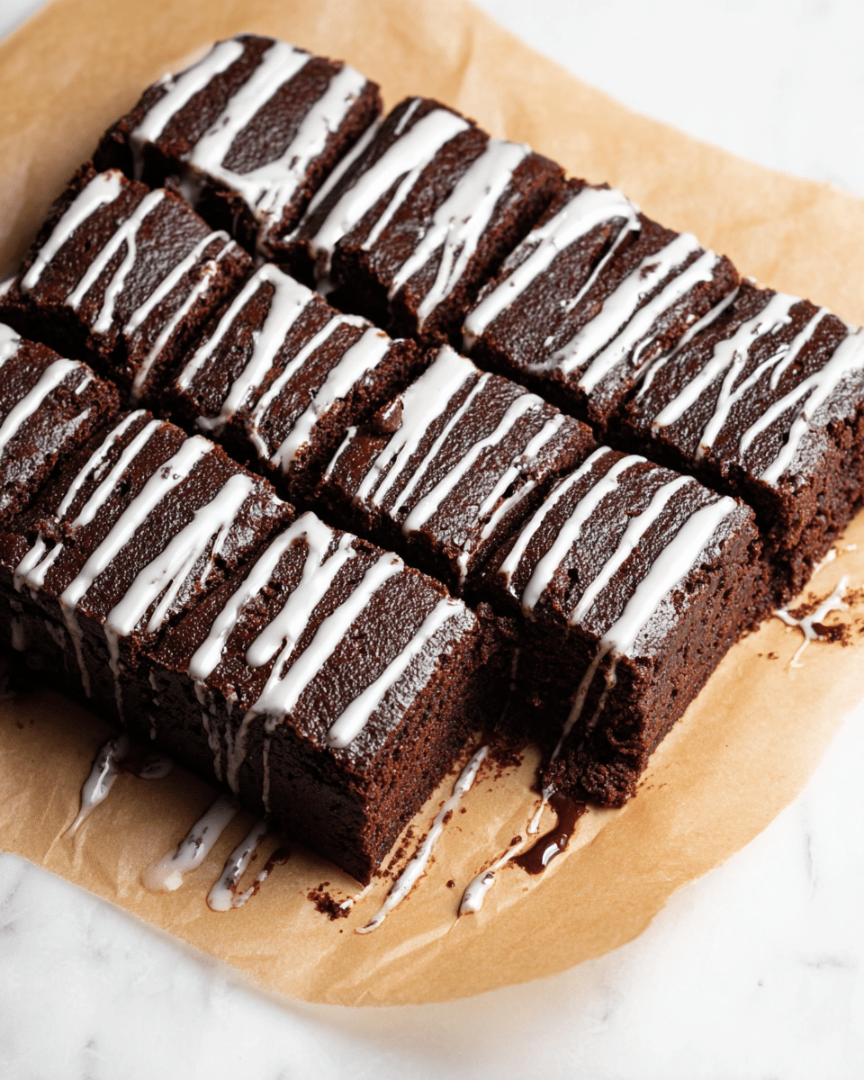 A rectangular dark brown chocolate brownie bar sits on a piece of light brown parchment paper on a white marbled surface. The brownie is cut into twelve square pieces arranged in three rows and four columns. A white glaze is drizzled in uneven lines across the top of the brownie, some glaze flowing down the sides and pooling lightly onto the parchment paper. The texture of the brownie looks dense and moist with a slightly rough surface, and the glaze contrasts sharply with the dark chocolate color. photo taken with an iphone --ar 4:5 --v 7