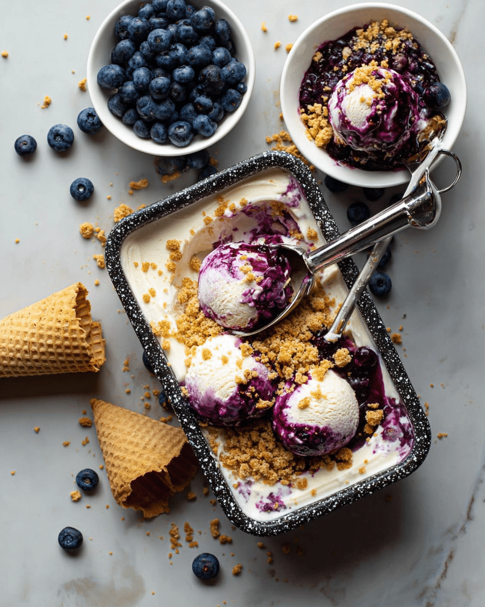 A white and black speckled rectangular container holds creamy white ice cream mixed with deep purple blueberry sauce, with some crunchy golden crumb topping scattered over the surface. There are three scoops of ice cream partially formed, with a silver ice cream scoop resting inside and covered in hints of purple sauce. Nearby, a white bowl is filled with fresh blueberries, and a white bowl contains more ice cream topped with blueberry sauce and crumbs, with a wooden lid leaning beside it. Fresh blueberries are scattered around on a white marbled texture background. Photo taken with an iphone --ar 4:5 --v 7