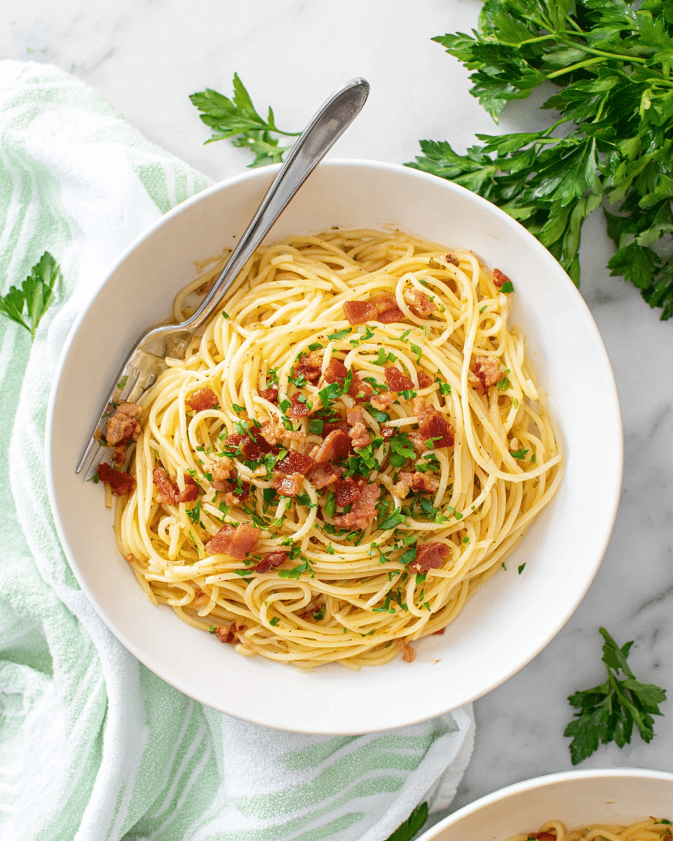 A white bowl contains a single layer of light yellow spaghetti arranged in a circular mound, topped with small pieces of crispy reddish-brown bacon and green chopped parsley scattered lightly on the surface. A silver fork rests inside the bowl on the left side, partially inserted into the spaghetti. The bowl is placed on a white marbled surface with a light green and white striped cloth partially underneath. Fresh green parsley leaves are scattered around the bowl. Photo taken with an iphone --ar 4:5 --v 7