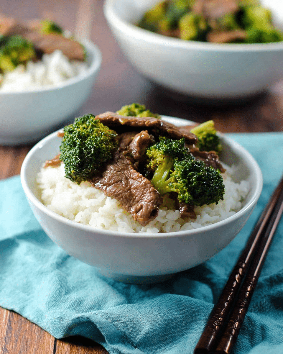 A white bowl filled with fluffy white rice as the bottom layer, topped with a layer of cooked beef slices and small bright green broccoli florets mixed together. The beef looks tender and slightly shiny with sauce. The bowl is placed on a light blue cloth on a wooden surface with another white bowl of rice and a white bowl of broccoli and beef in the background. Dark brown chopsticks rest beside the bowl on the cloth. photo taken with an iphone --ar 4:5 --v 7